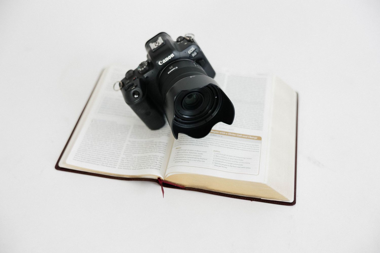 Open book and camera arranged on white background for minimal photography composition.