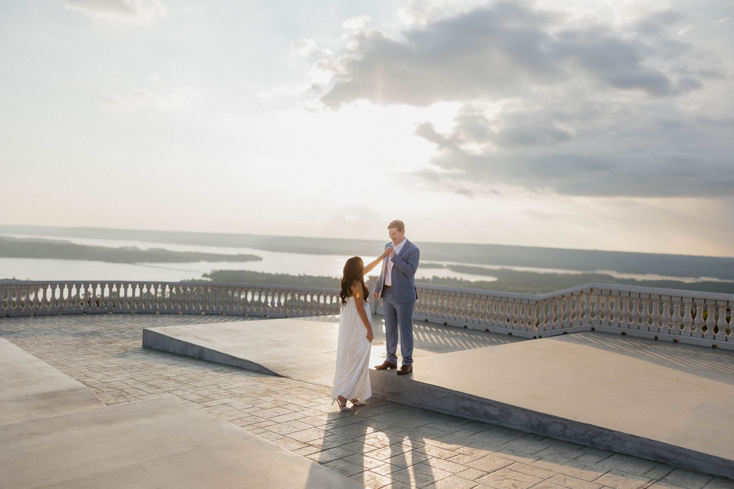 White stone balcony railing overlooking a scenic coastal landscape at dusk.