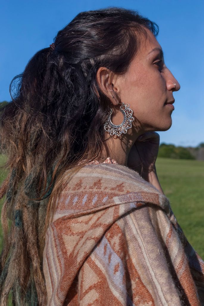 Profile Portrait of a young woman modeling a earrings for a bohemian apparel brand in a field