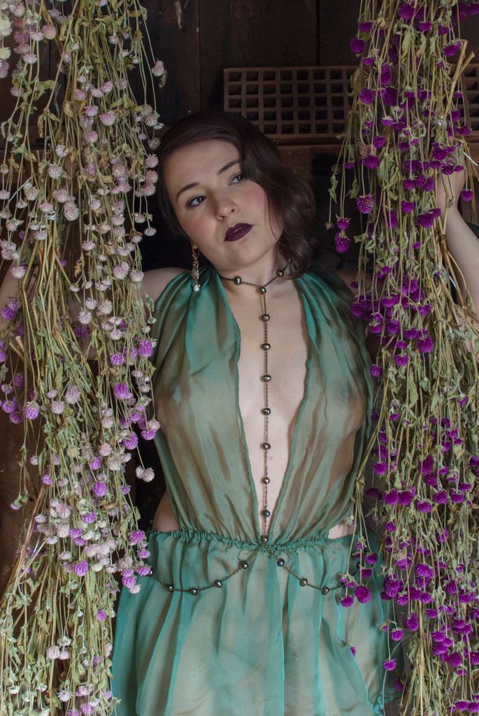 Boudoir portrait of a young woman between two floral garlands modeling self-made lingerie