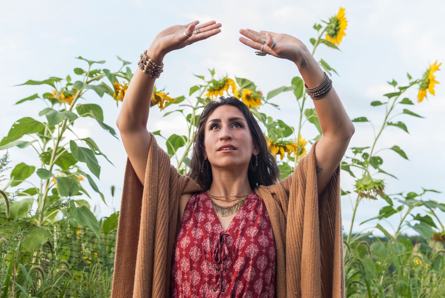 Lifestyle portrait of a young women with dreadlocks in a sunflower field