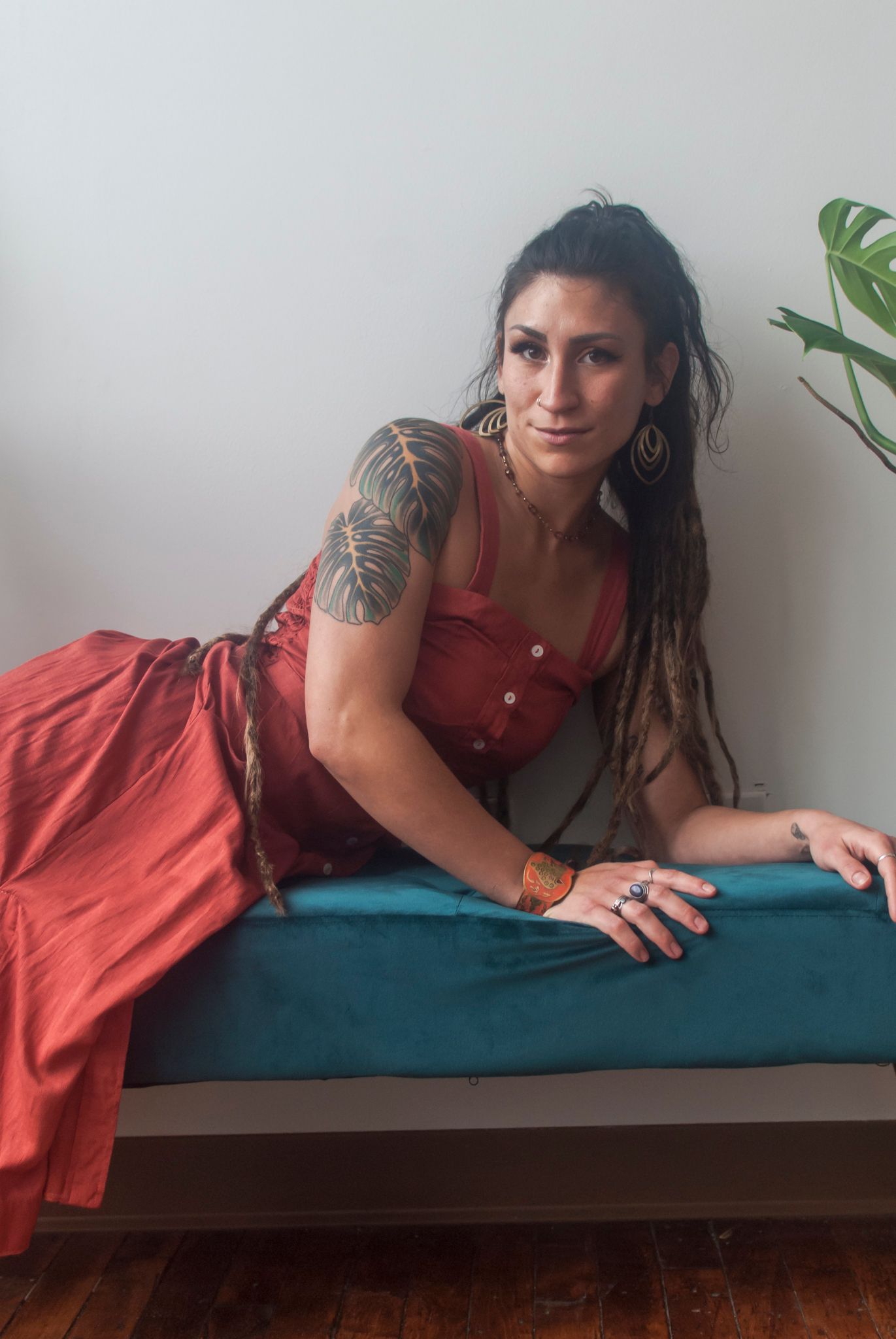 Lifestyle portrait of a young woman with tattoos lounging on a bench in a studio