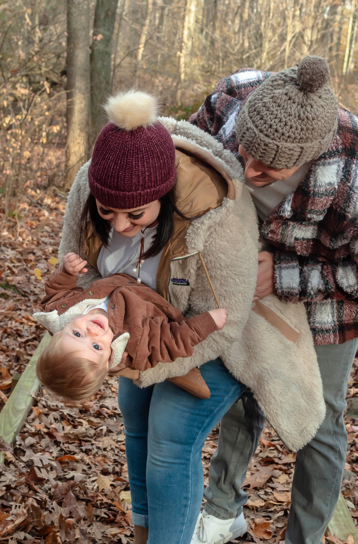 Family portrait of parents and young child outdoors in a wooded autumn setting