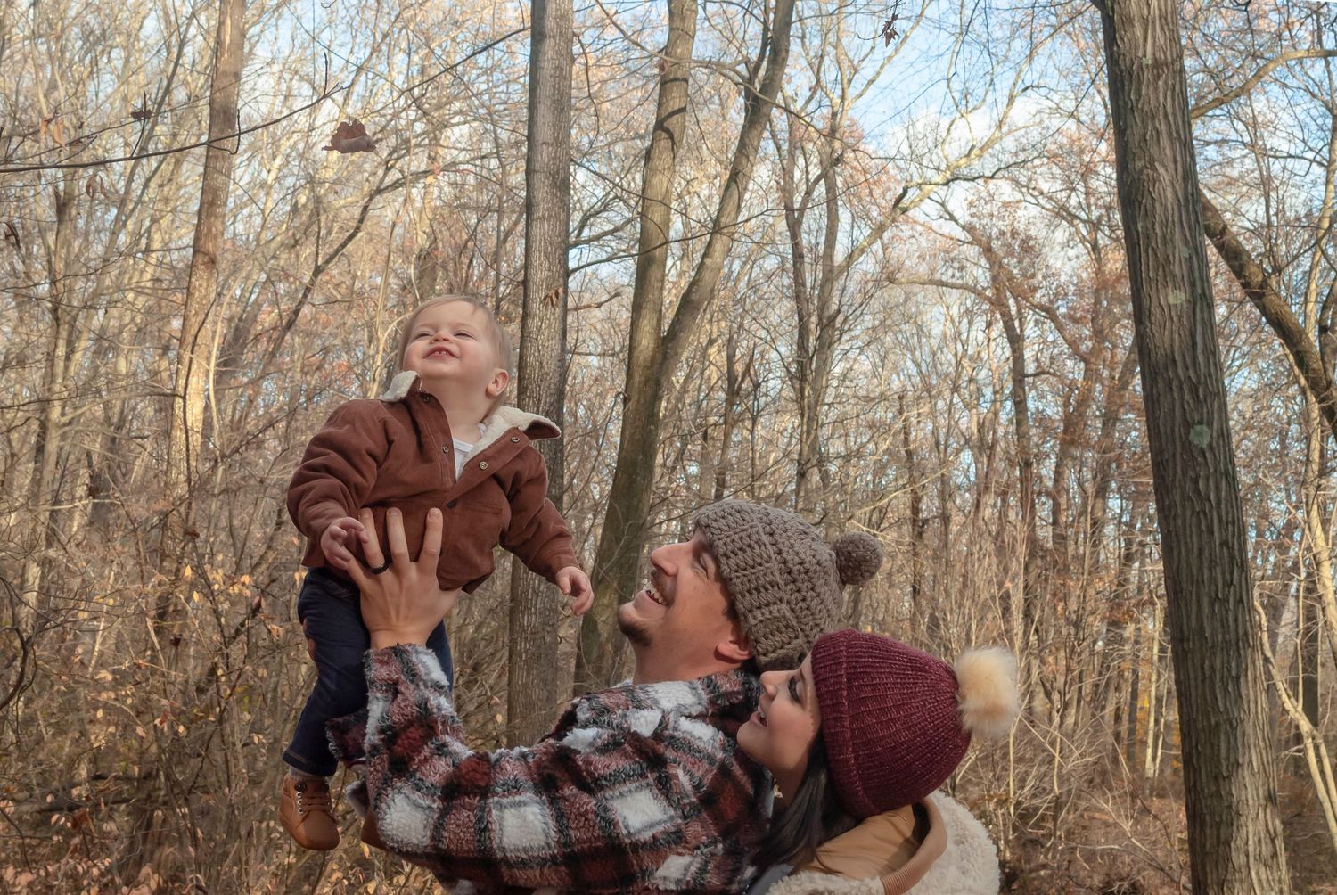 Family portrait of parents and young child outdoors in a wooded autumn setting