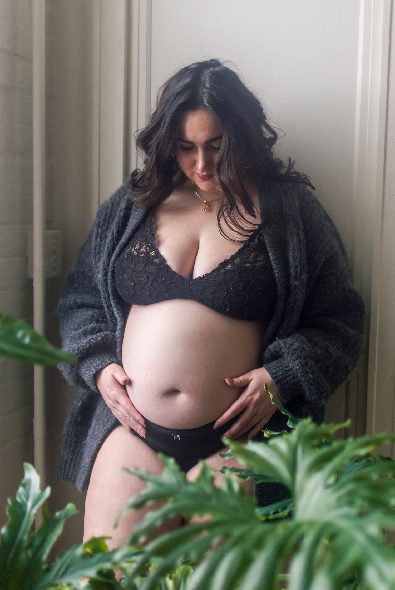 Lifestyle portrait of a pregnant woman standing near a window in a uniquely curated, natural light photography studios in Hartford, CT