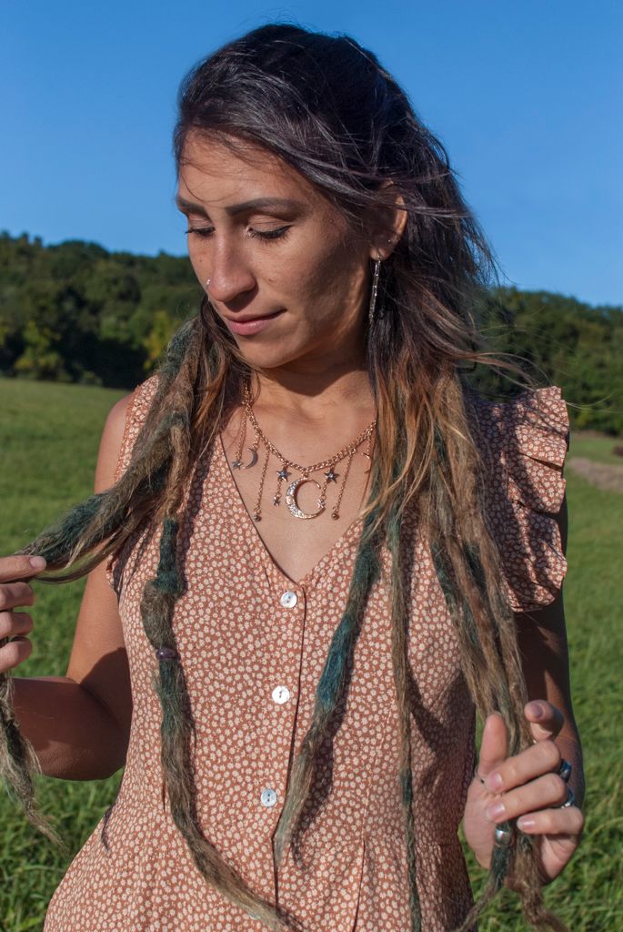 Portrait of a young woman modeling a celestial necklace for a bohemian apparel brand in a field