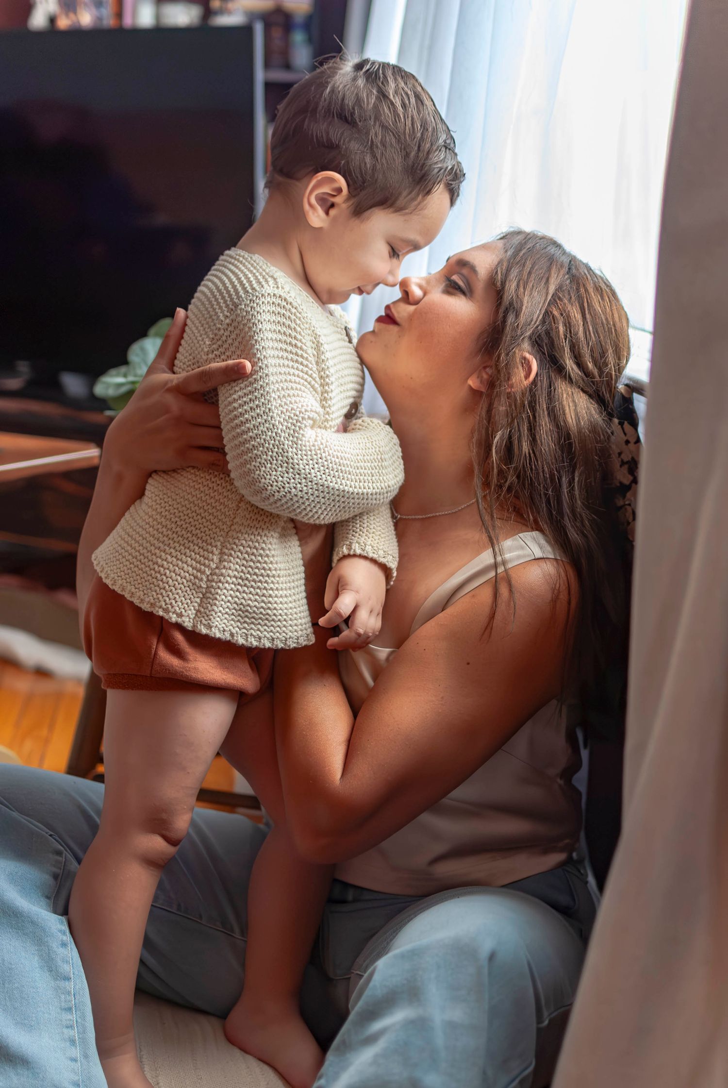Lifestyle portrait of a Mother and child standing near a window