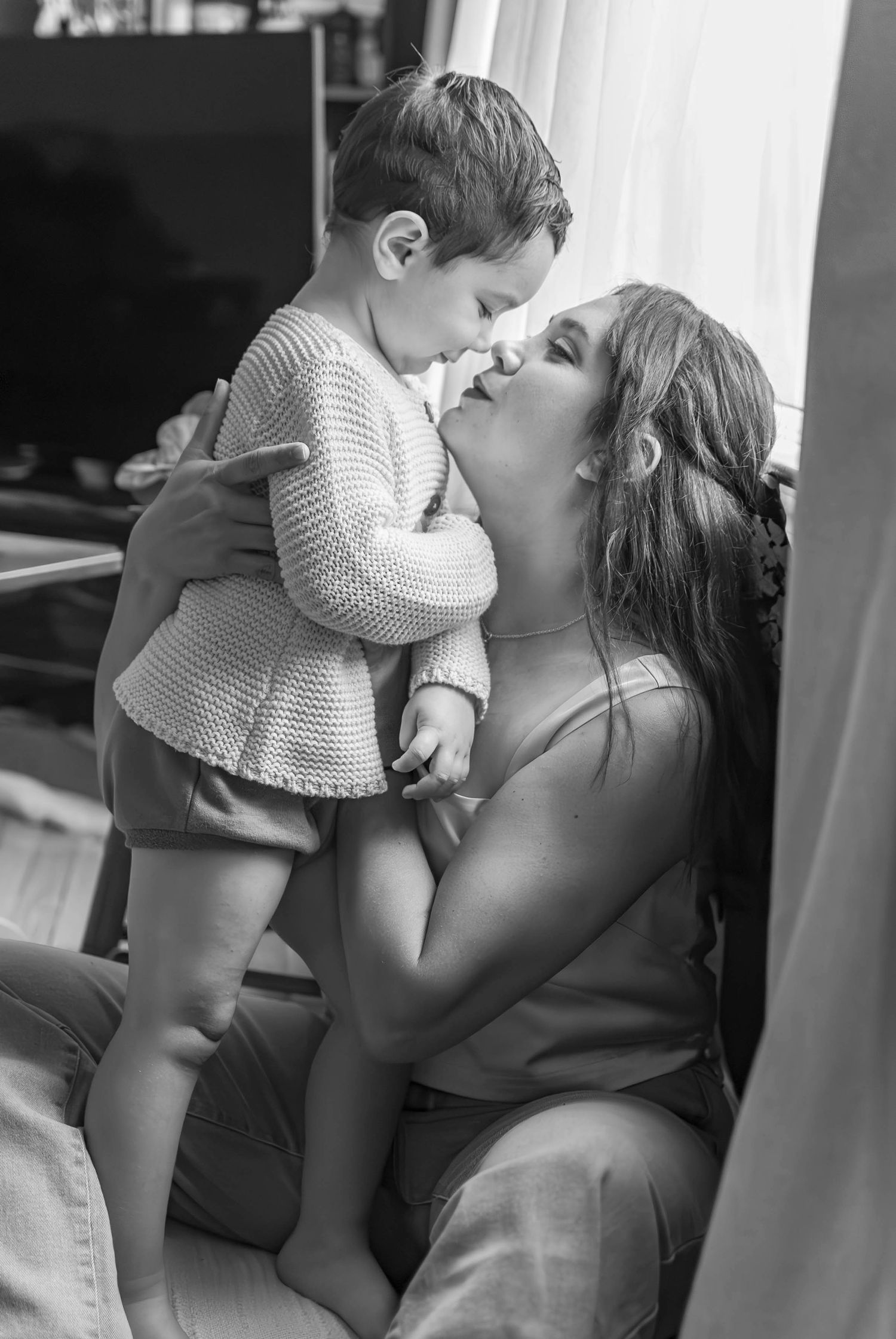 Black and White Lifestyle portrait of a Mother and child standing near a window