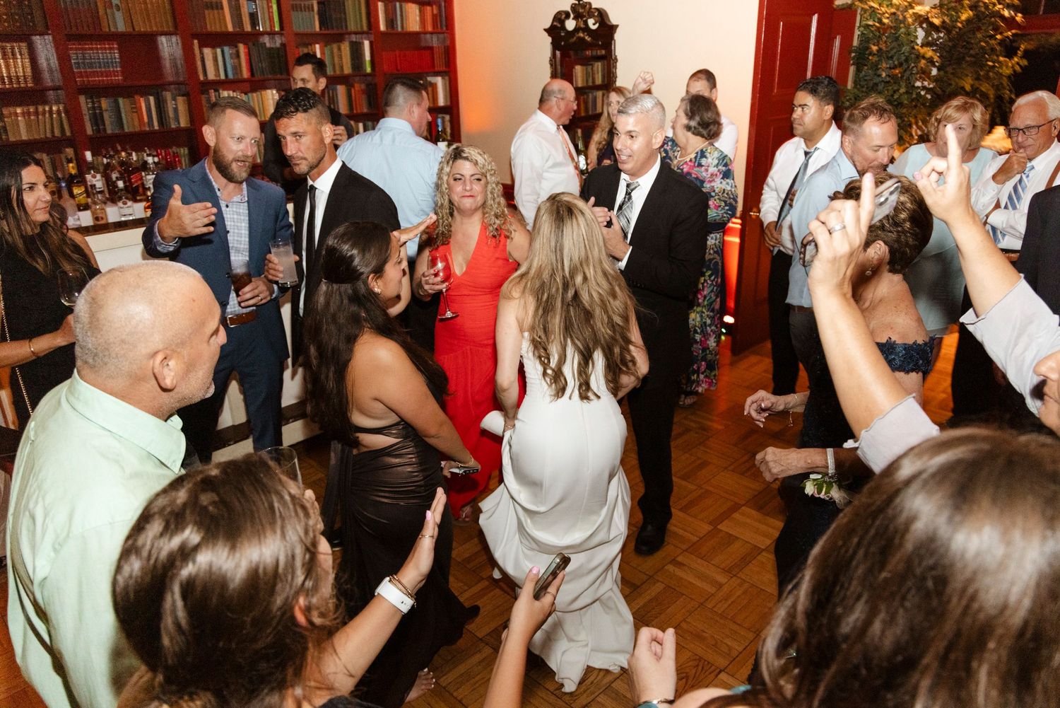 Large group of wedding guests dancing and mingling at an indoor reception venue. Rochester NY candid wedding photography