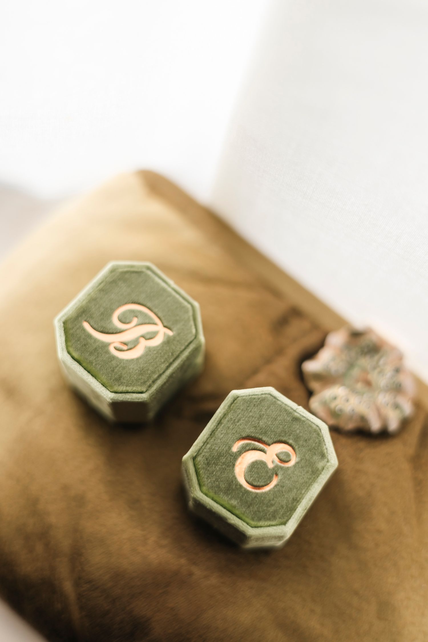 Green hexagonal cufflinks with delicate script lettering displayed on a brown textured surface. Film wedding photographer Rochester  NY
