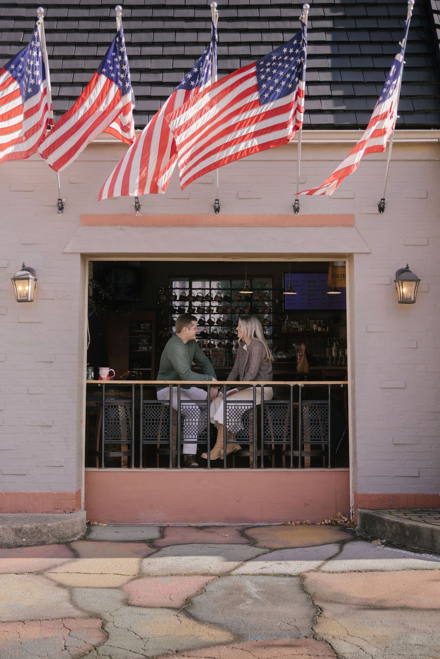 American flags line the exterior of a brick building with pink accents.