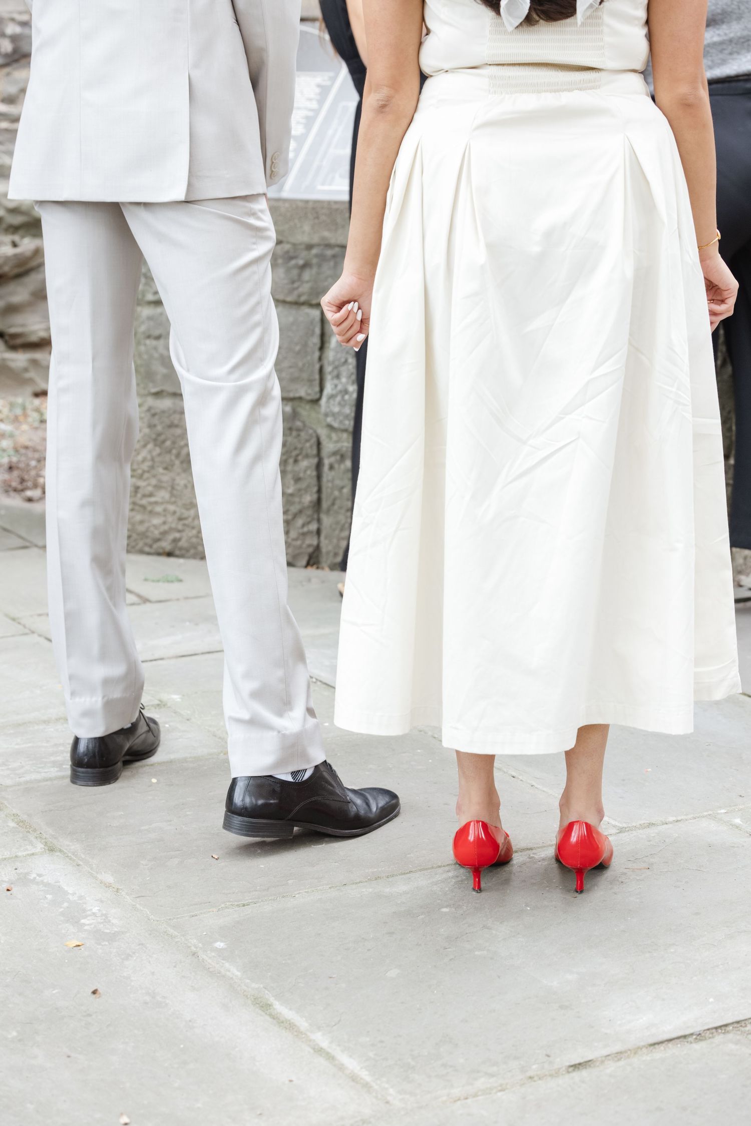 Formal wedding attire detail showing white suit pants and red heels against stone ground.  St. Josephs park wedding photographer
