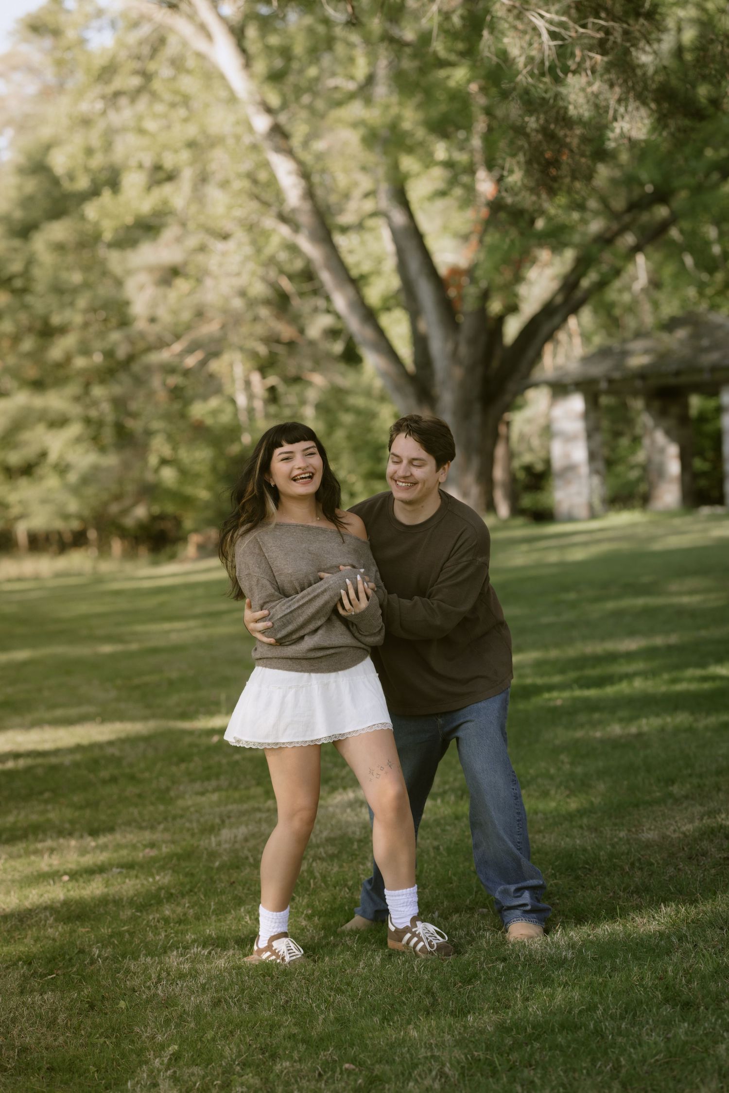 A pair dances together on a grassy hillside surrounded by trees.  Rochester NY film engagement photography