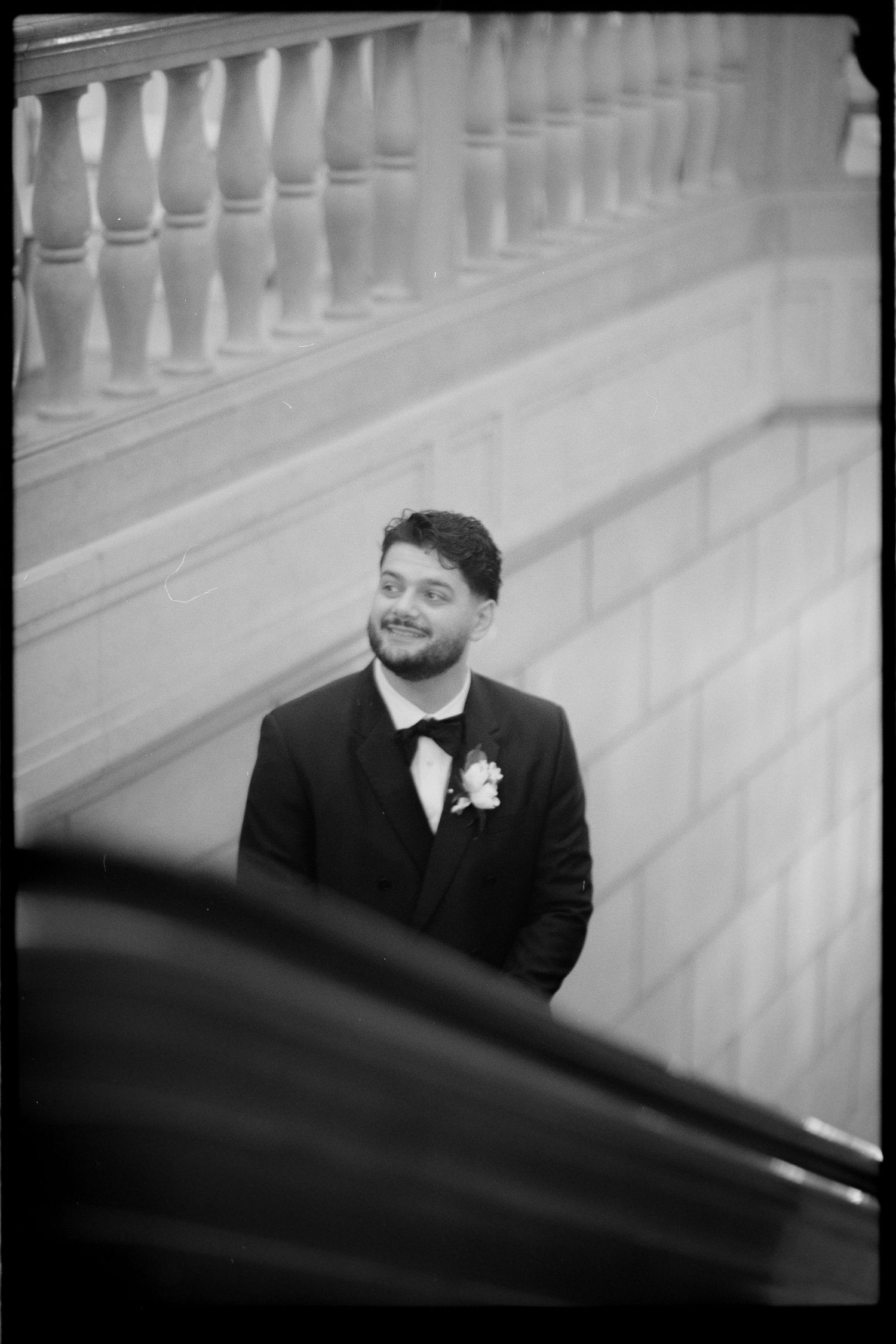 Black and white sequence of a groom smiling in formal attire against a white architectural backdrop. Arbor Midtown wedding photographer
