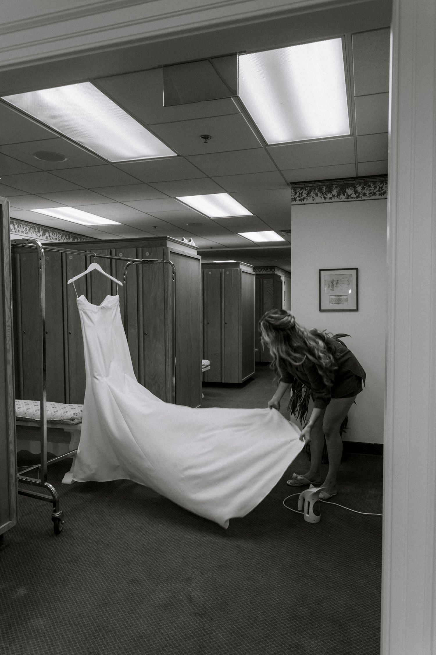 Wedding dress being carried through a hallway in dramatic black and white photography.Rochester NY documentary wedding photography