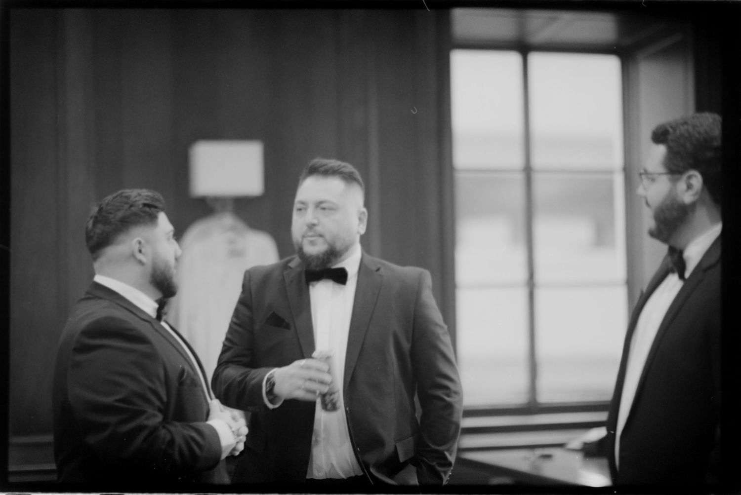 Black and white shot of three guests in formal wear conversing at an event.