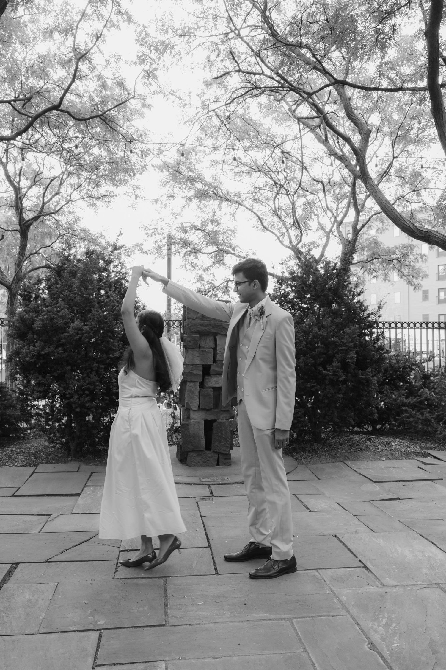 A black and white photo of a couple standing on stone pavement in a garden setting.  St. Josephs park wedding photographer