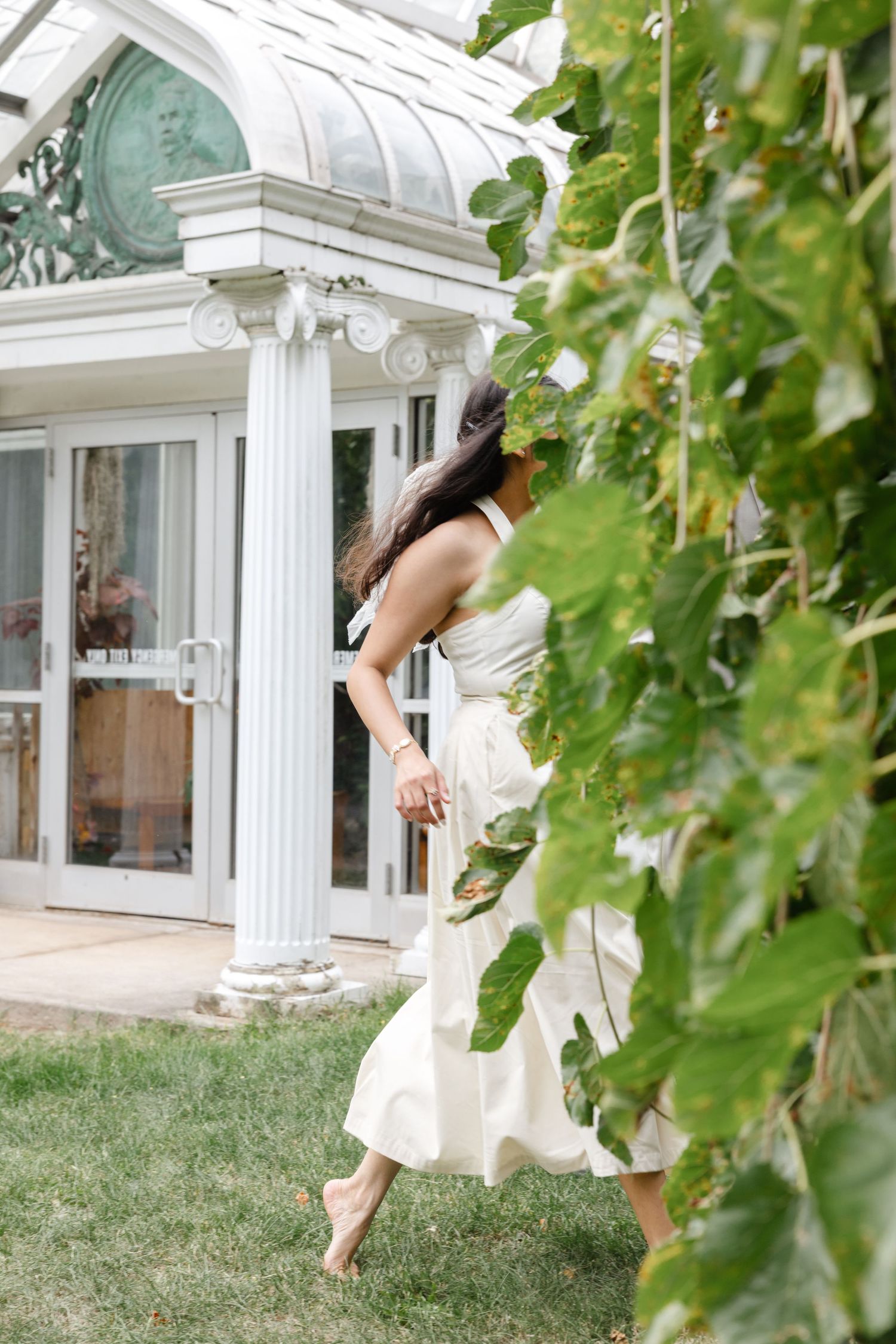 Couple dances near a white conservatory with green vines hanging in the foreground. Highland Park elopement photographer Rochester  NY