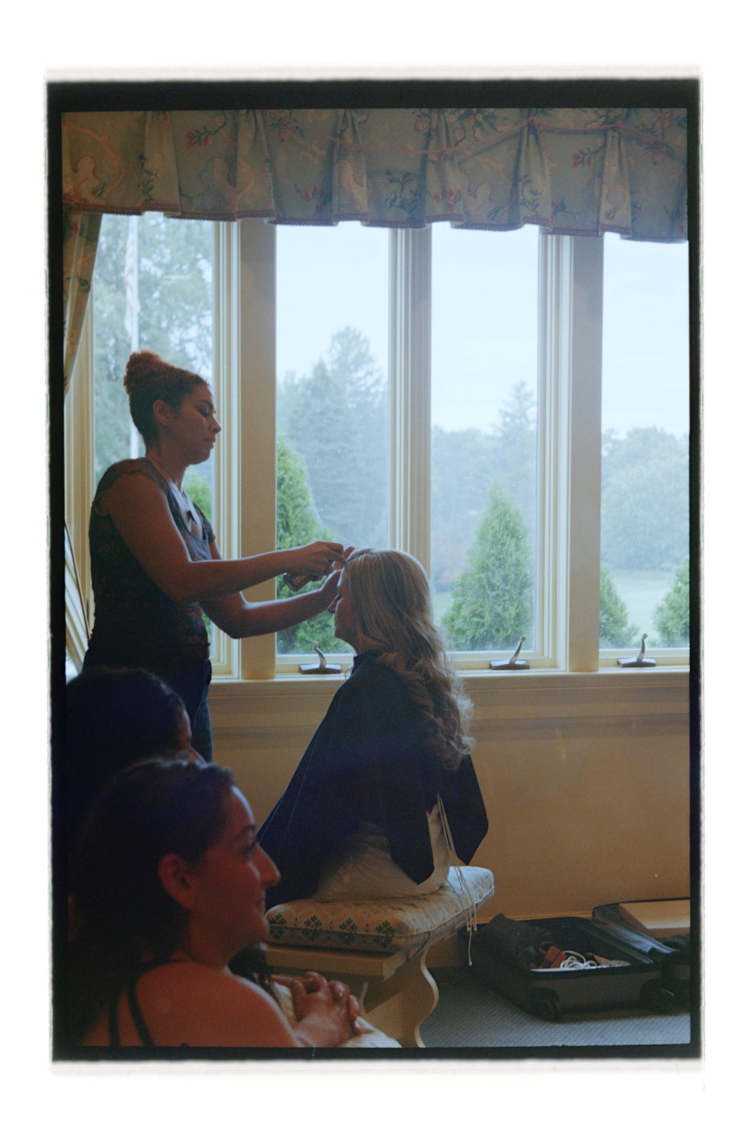 People preparing for special event by window with natural lighting. Rochester NY Film wedding photography