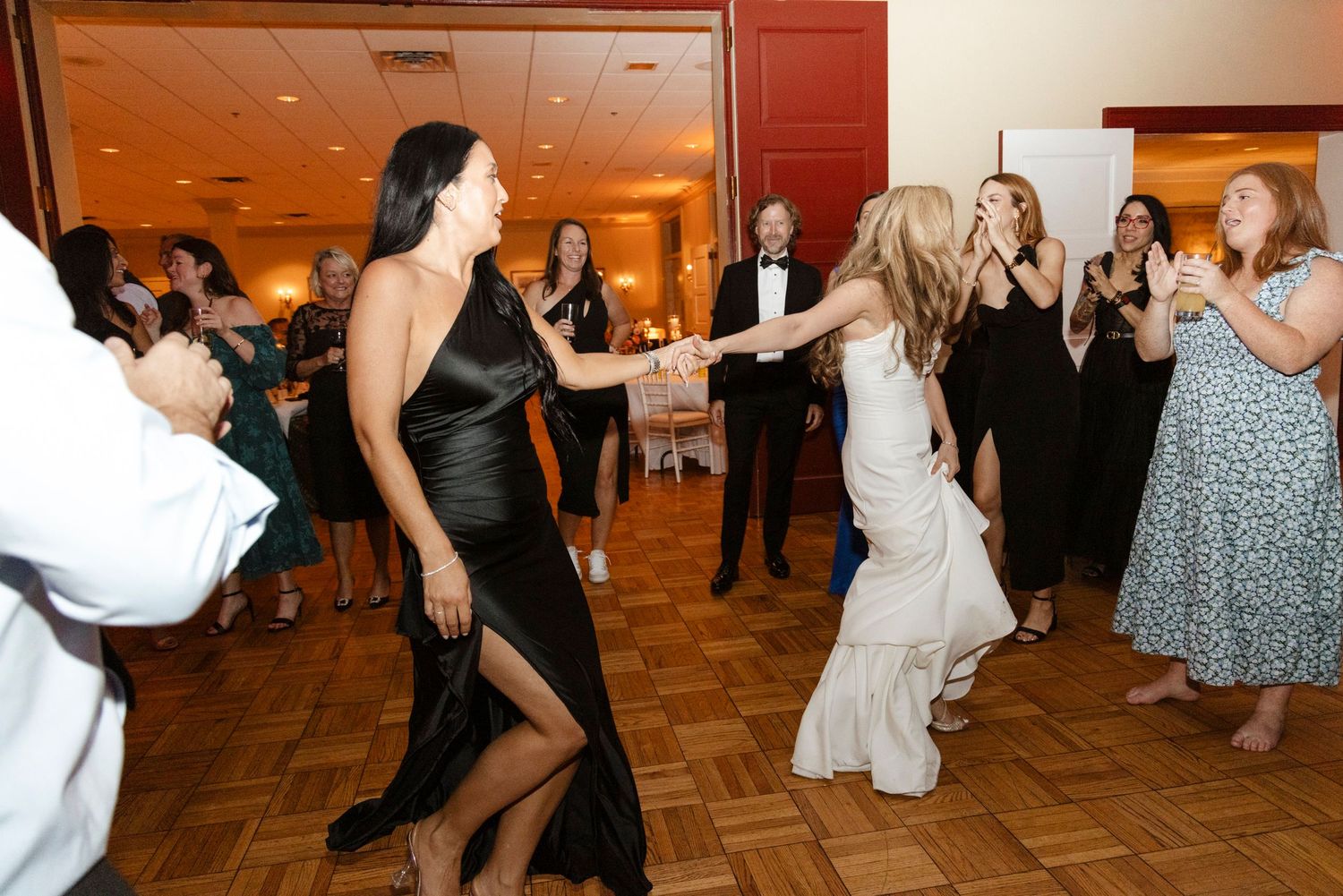 Couples dancing together at a formal event with wooden floors and ambient lighting. Rochester NY candid wedding photography