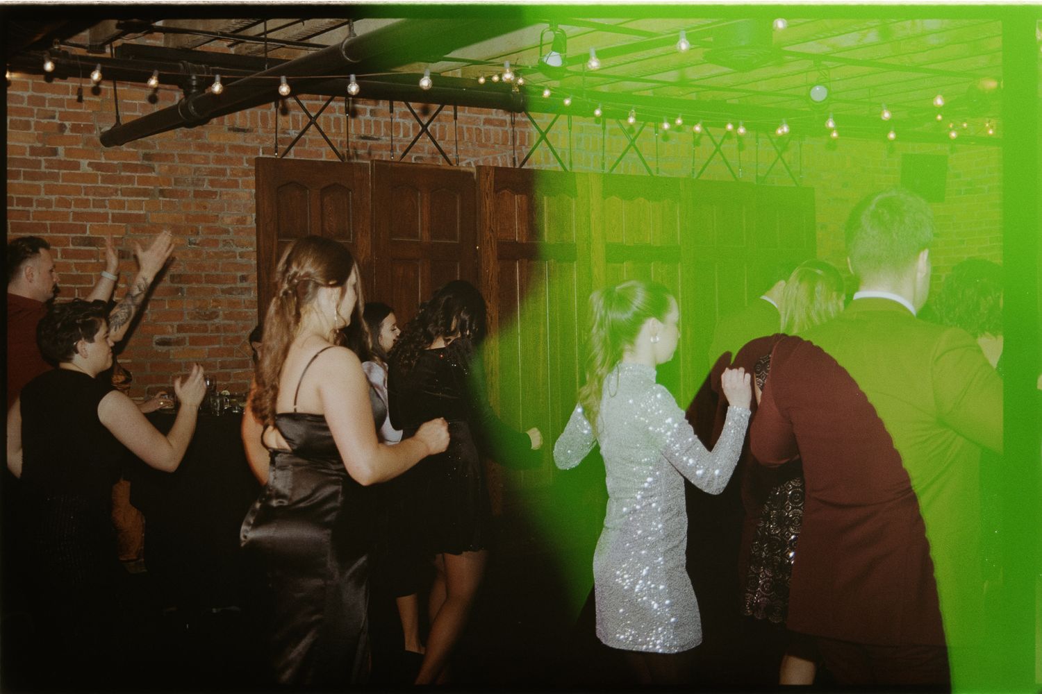 People dancing at a party venue with string lights and exposed brick walls under green lighting effects.