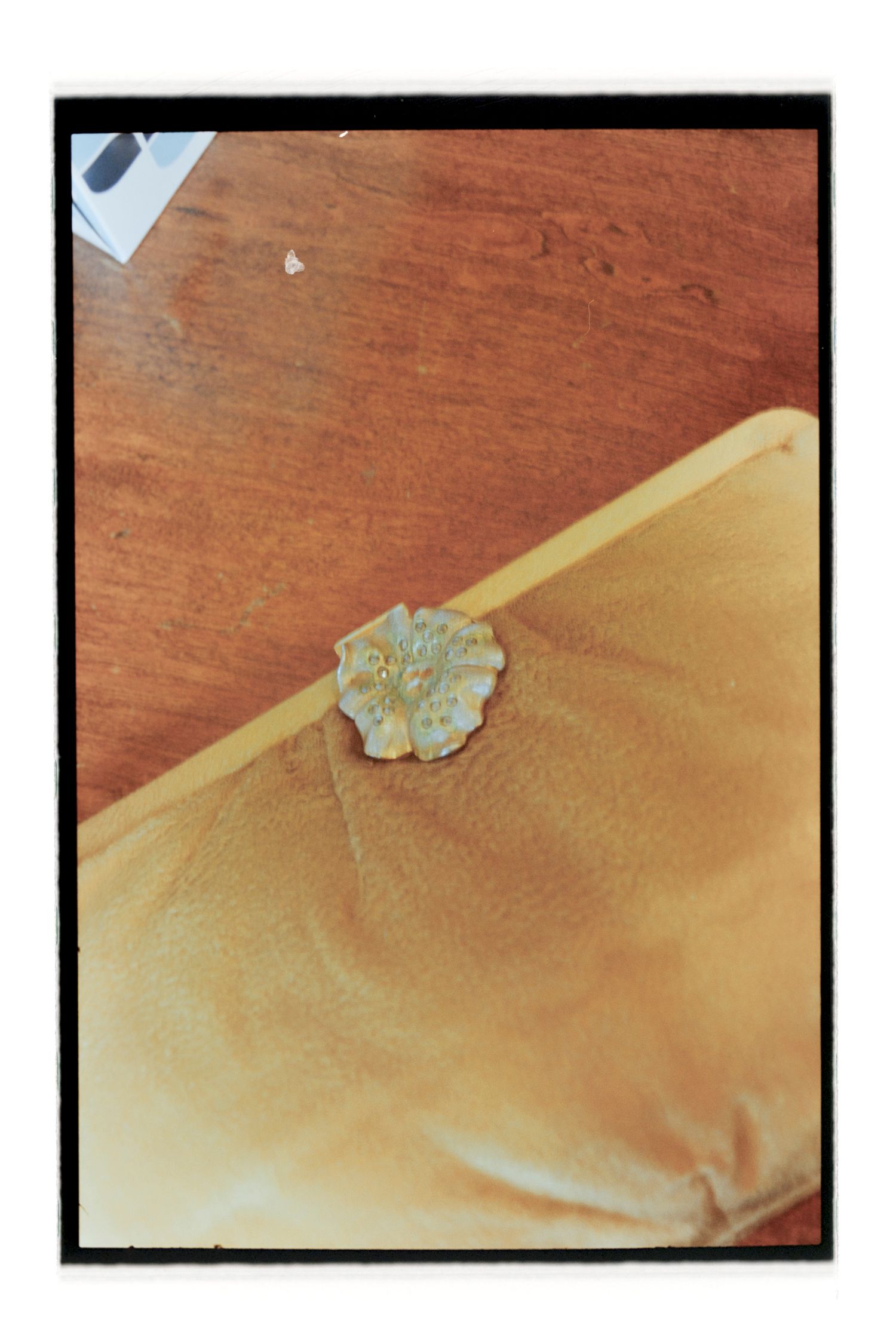 Decorative silver brooch on yellow fabric surface.  Rochester NY Film wedding photography