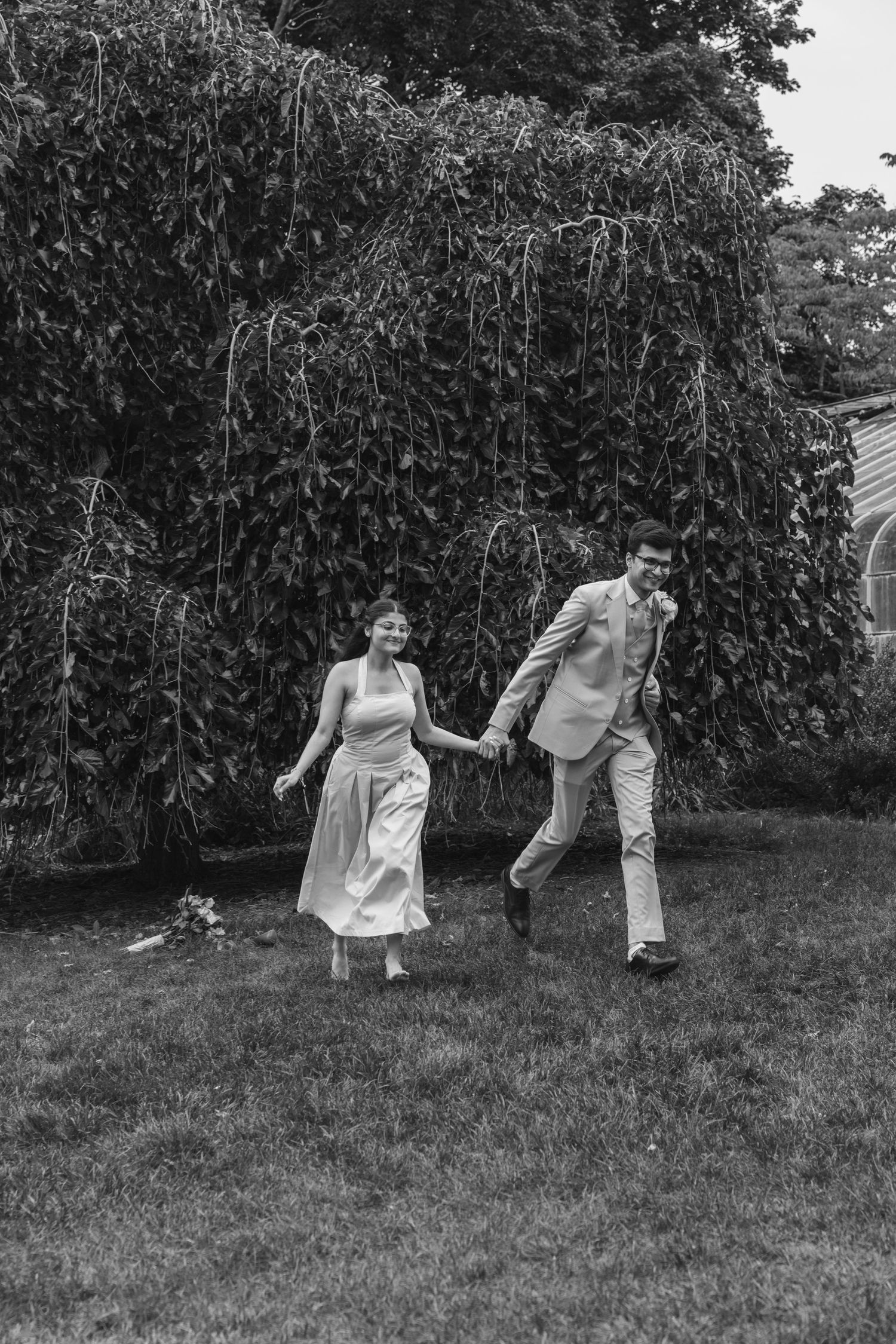 Black and white photos capture a couple dancing joyfully on grass near hedges. Highland Park elopement photographer Rochester  NY