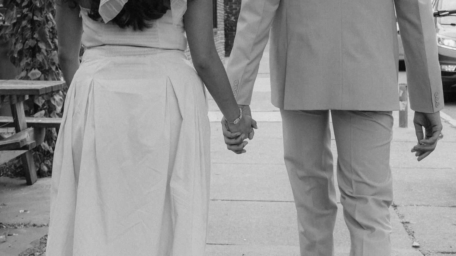 A black and white photo of two people holding hands while walking together.  Fun elopement photography Rochester NY
