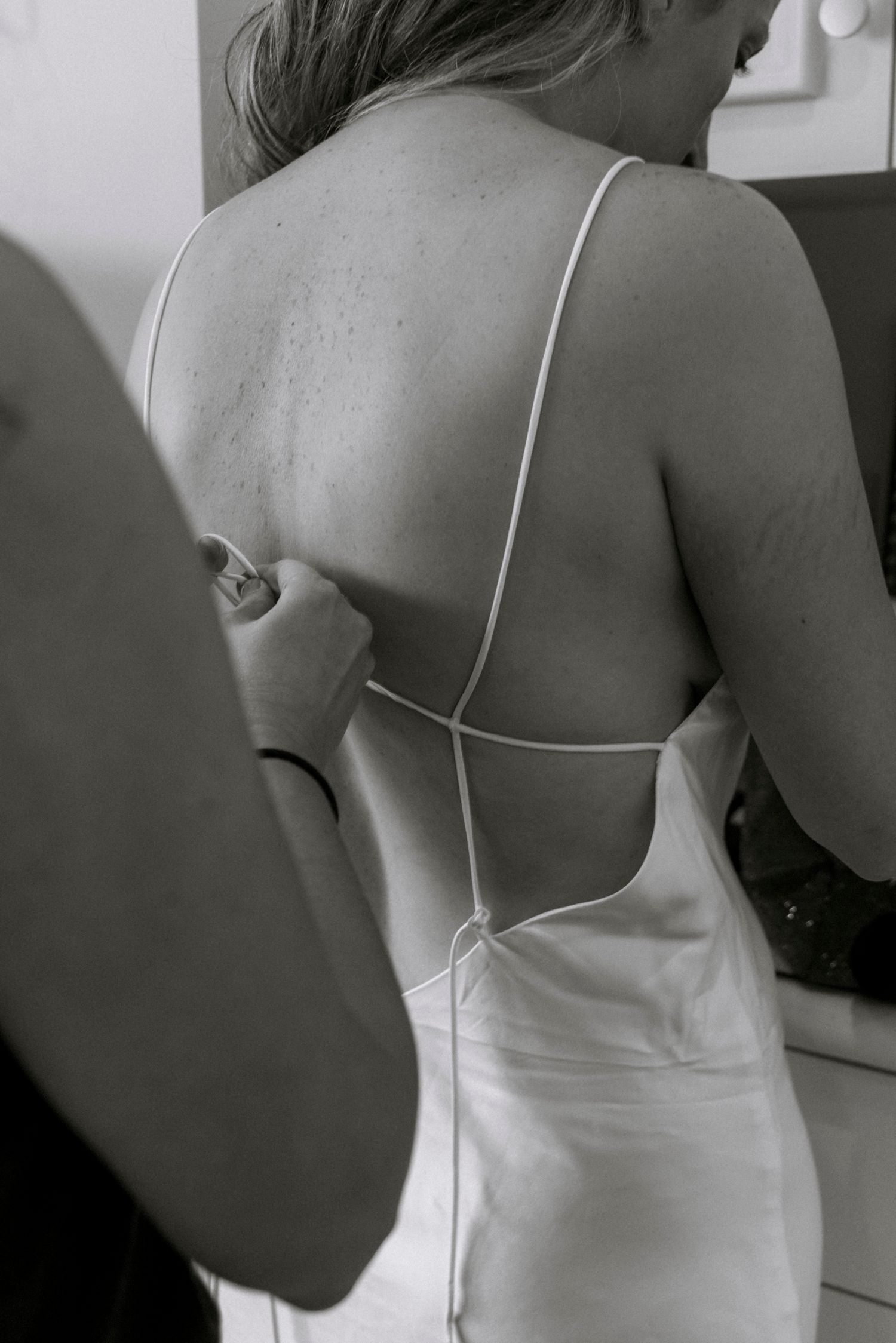 Back detail of white wedding dress showing delicate spaghetti straps.Rochester NY documentary wedding photographer