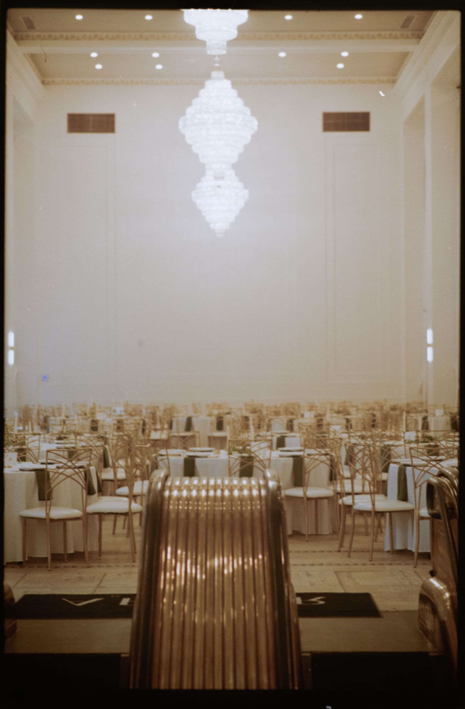Empty banquet hall set up for a wedding with cream-colored chairs and elegant table settings. . Arbor Midtown wedding photographer