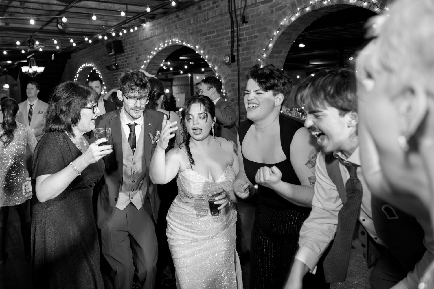 A black and white image of a group of people dressed up and dancing at a party.