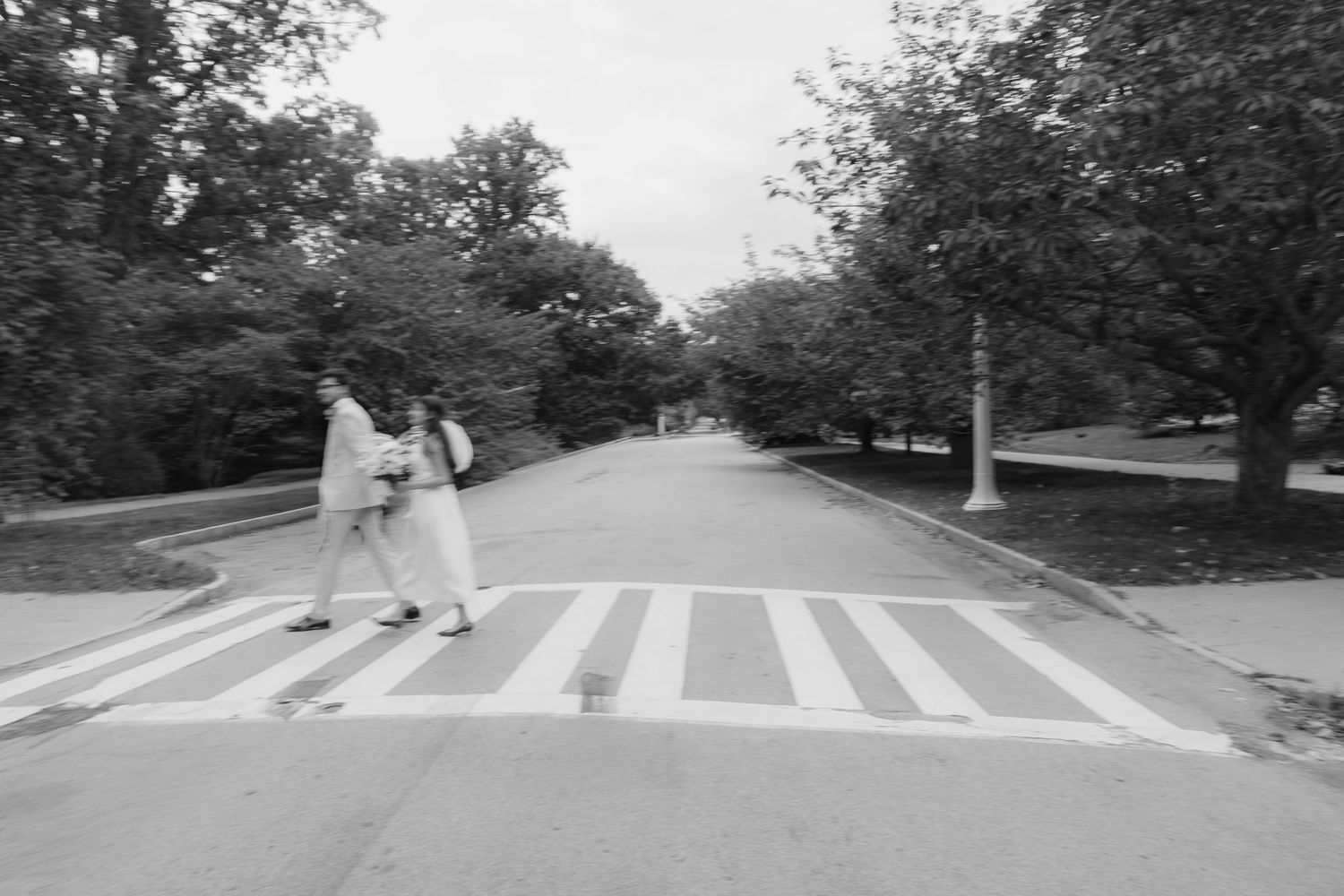 Black and white series showing a couple crossing a pedestrian crosswalk.  Rochester NY conservatory wedding photographer