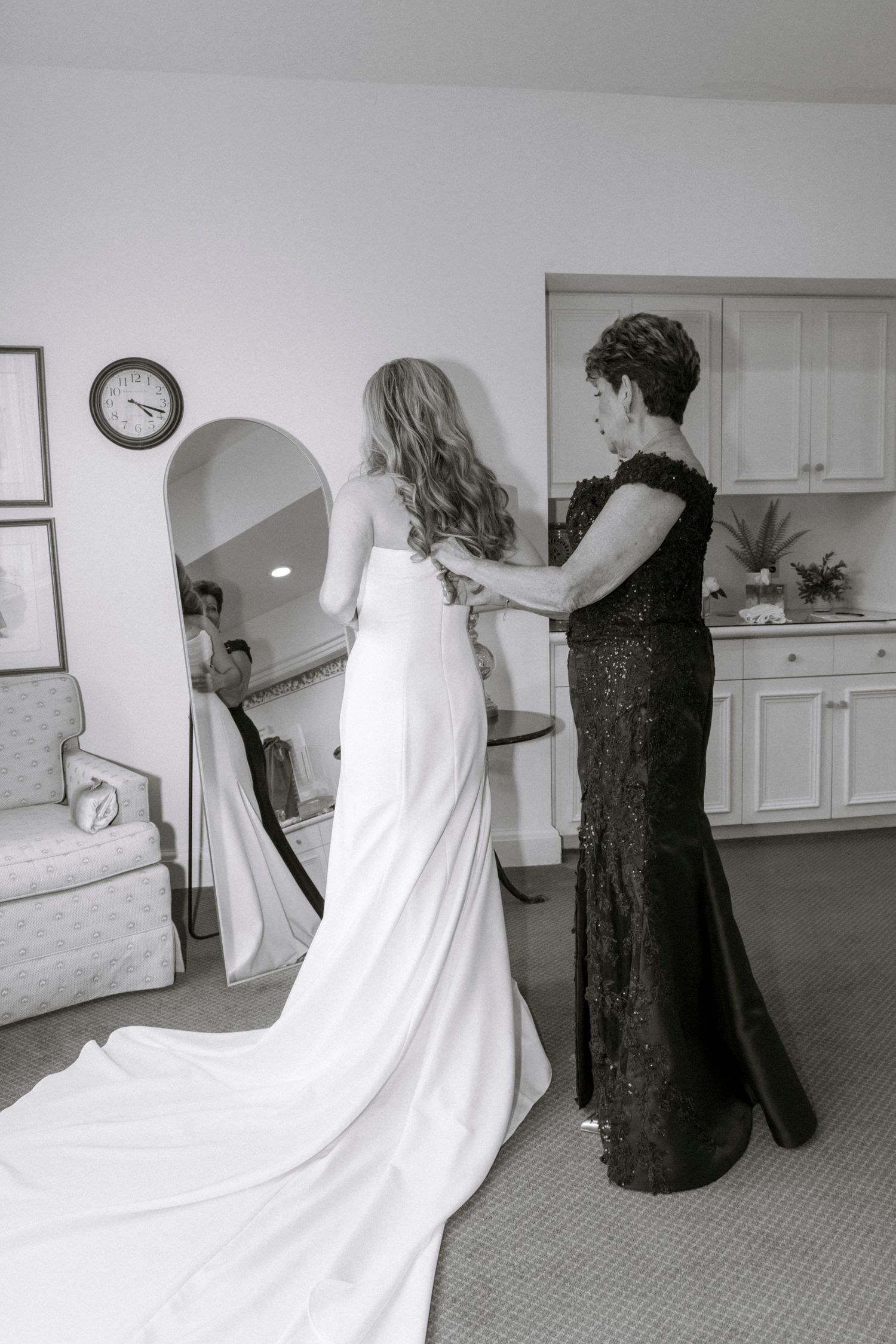 A wedding dress fitting scene with a long white gown being adjusted in an elegant room.Rochester NY documentary wedding photographer