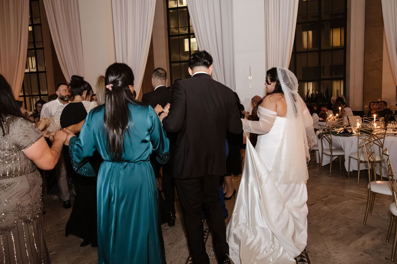 Wedding guests dancing and celebrating at an elegant venue with white drapes. Arbor Midtown wedding photographer