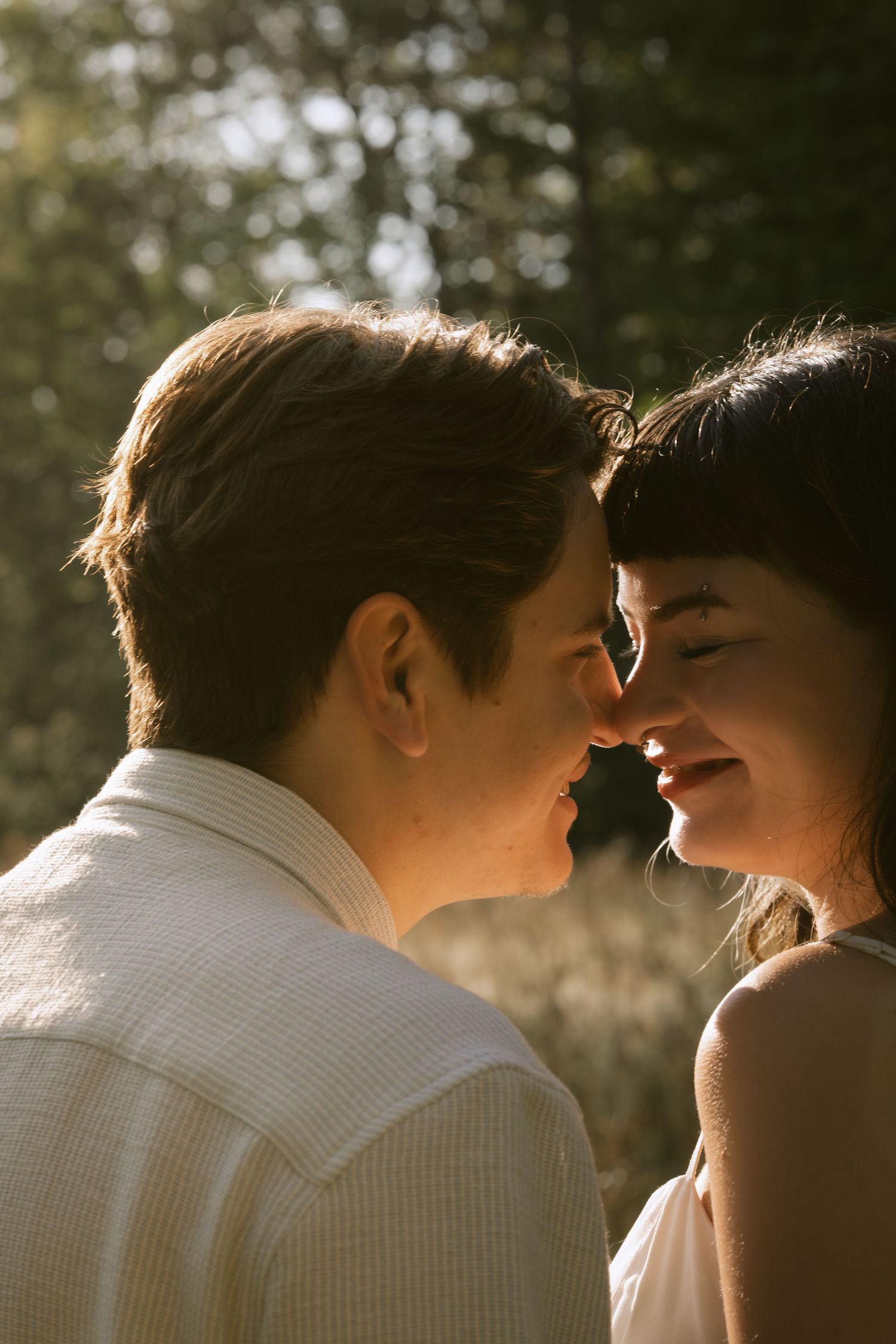 An intimate close-up portrait of a couple sharing a tender moment in warm sunlight.  Rochester NY film engagement photography