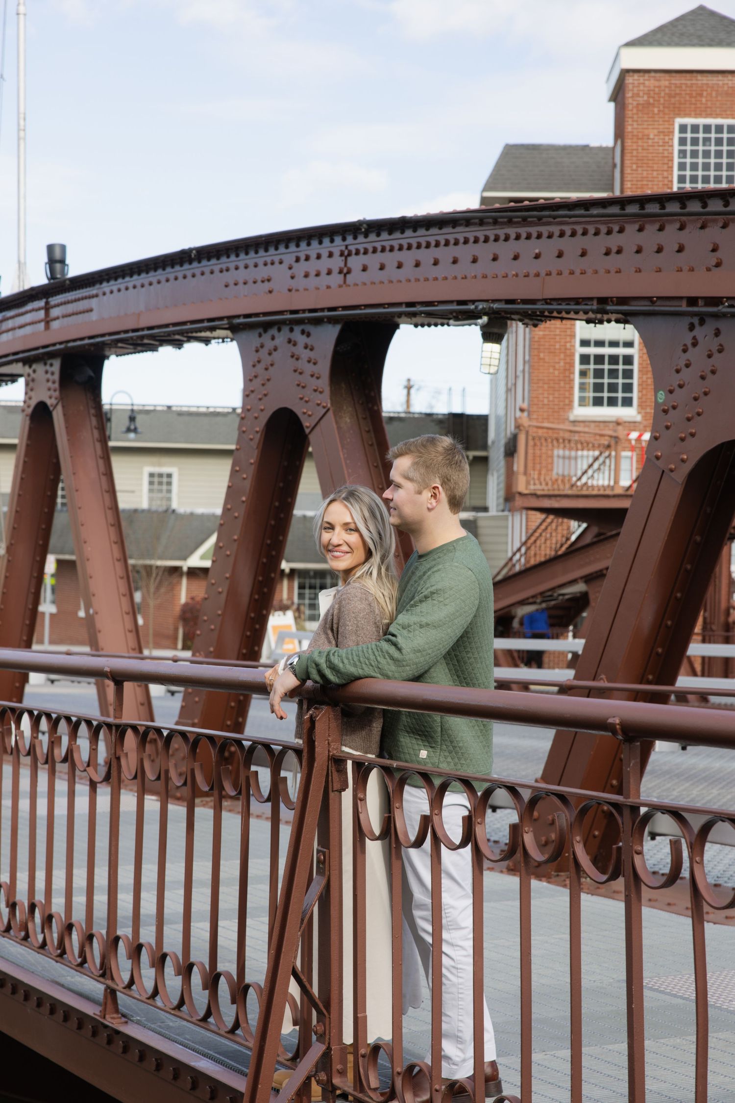 A couple shares a romantic moment on an iron bridge with ornate railings and architectural details. Film wedding photographer Rochester  NY