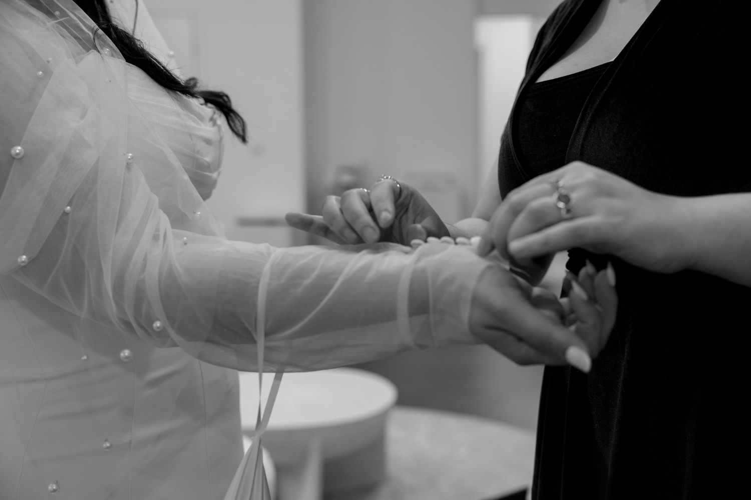 Close-up black and white shot of hands exchanging rings during a wedding ceremony.