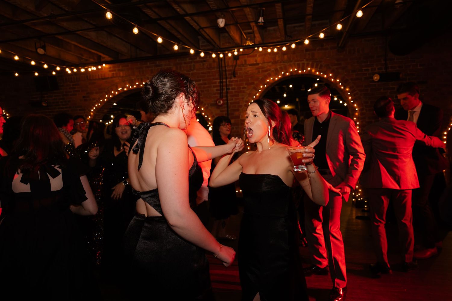 A group of people dancing in a dimly lit room with string lights and festive decor.