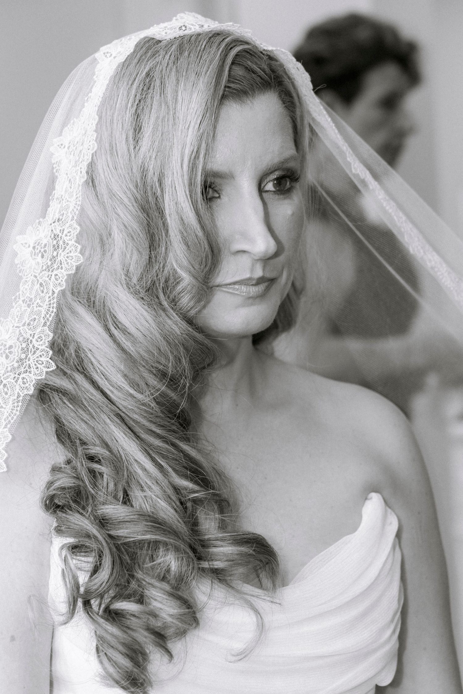 Elegant bridal portrait in black and white showing lace veil and styled curls. Film wedding photographer NY