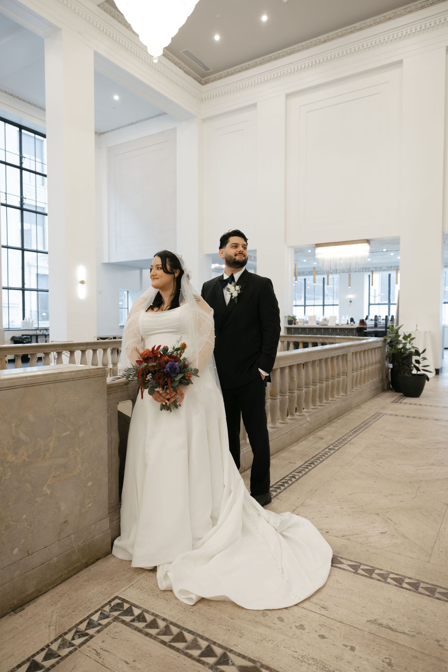Wedding couple poses in an elegant marble hallway with tall windows and ornate architectural details. Arbor Midtown wedding photographer