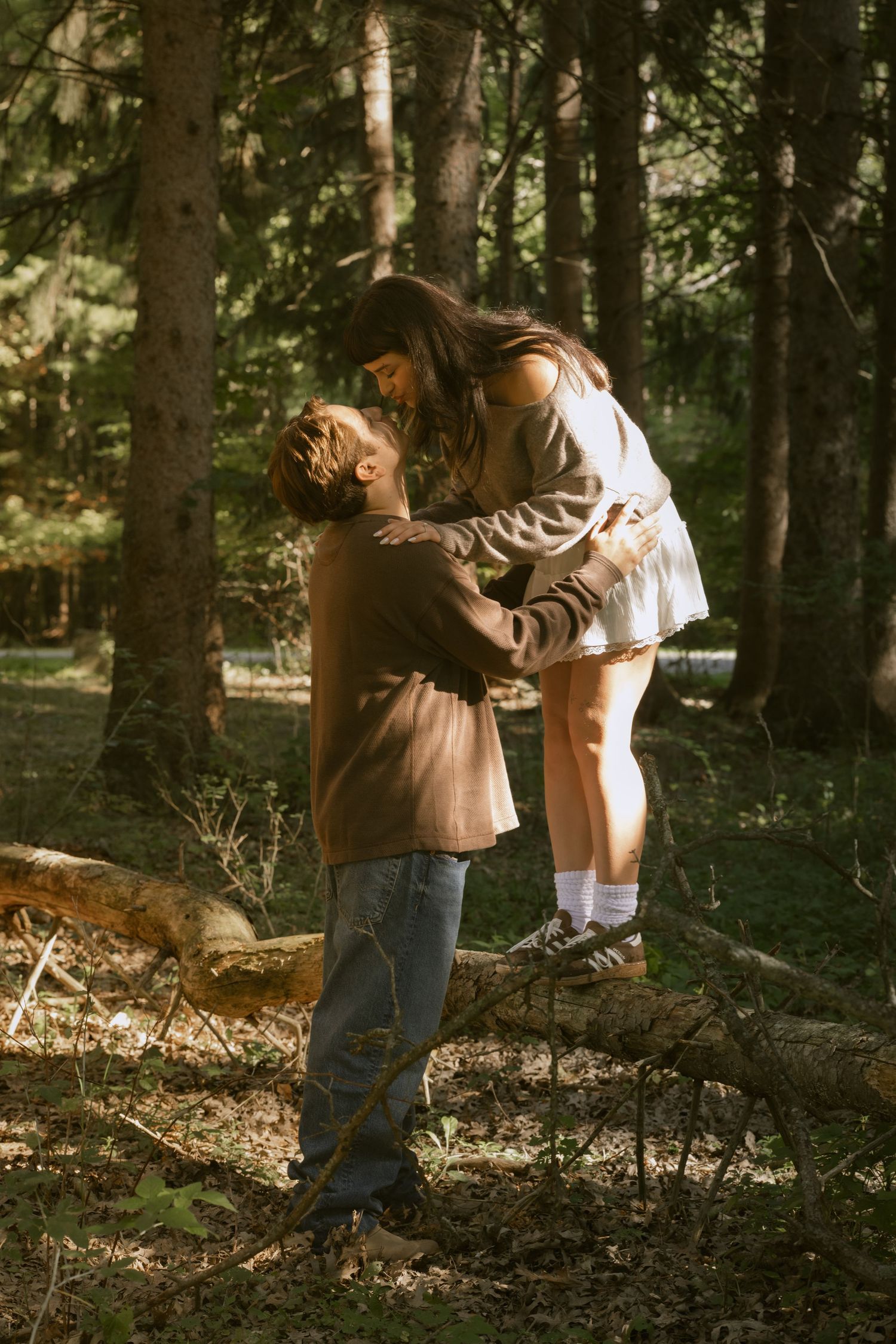 A couple dances playfully together in a wooded forest setting. Rochester NY documentary engagement photography