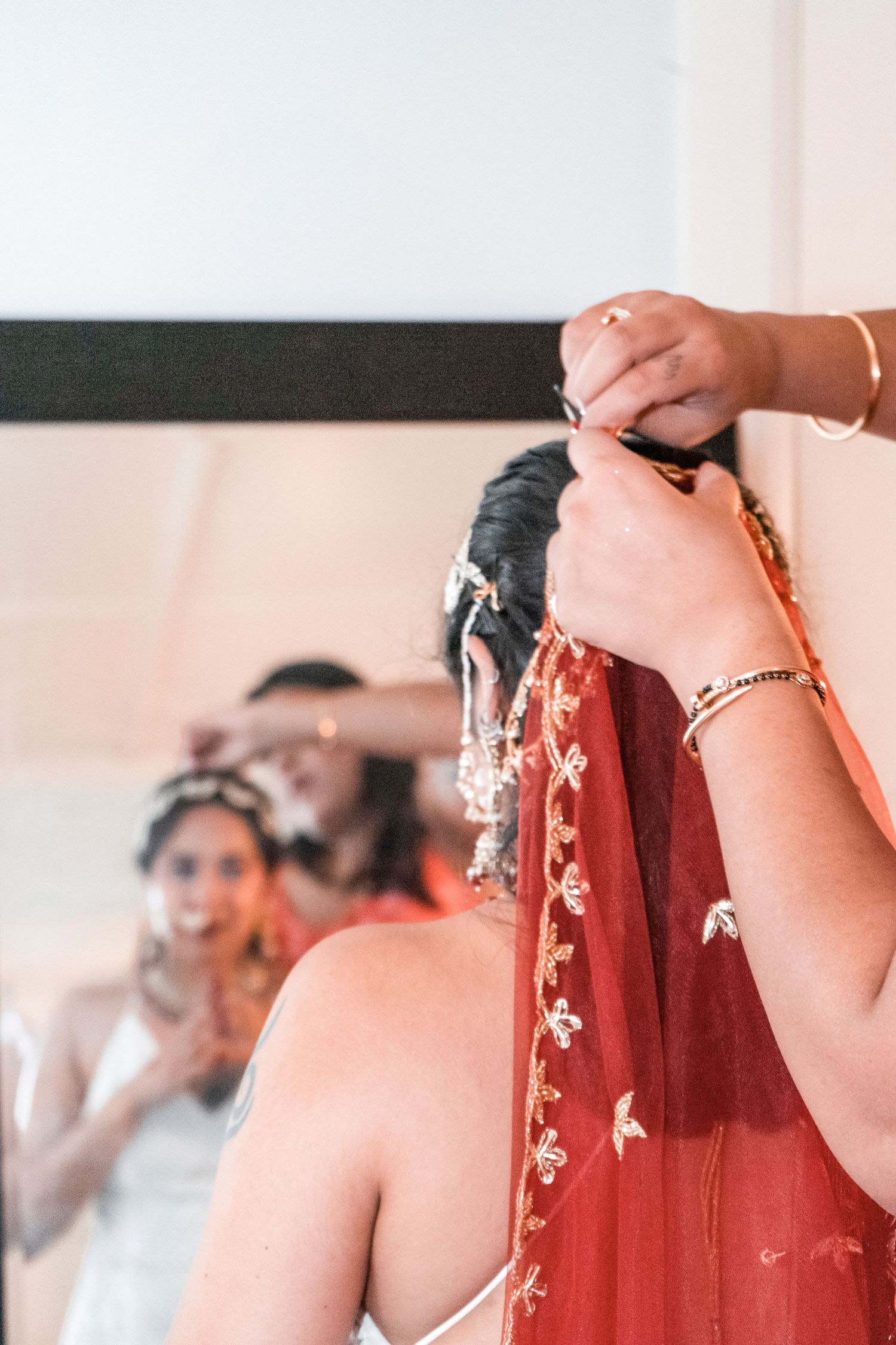 Hands arranging red fabric with delicate embroidered details during wedding preparations. Ithaca outdoor wedding photographer