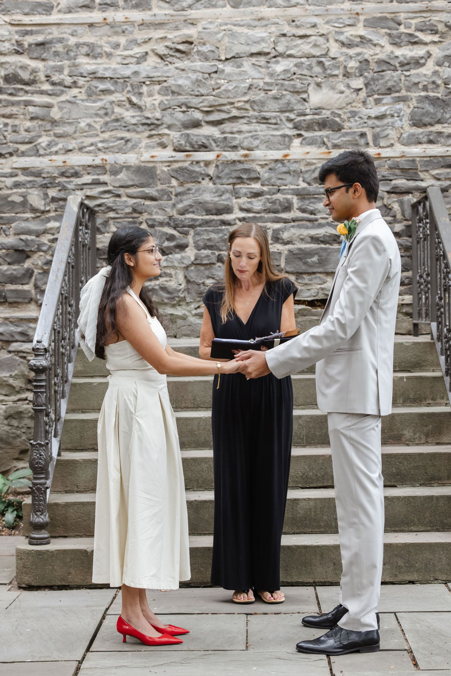 Intimate wedding ceremony taking place on stone steps with officiant in black dress.  St. Josephs park wedding photographer