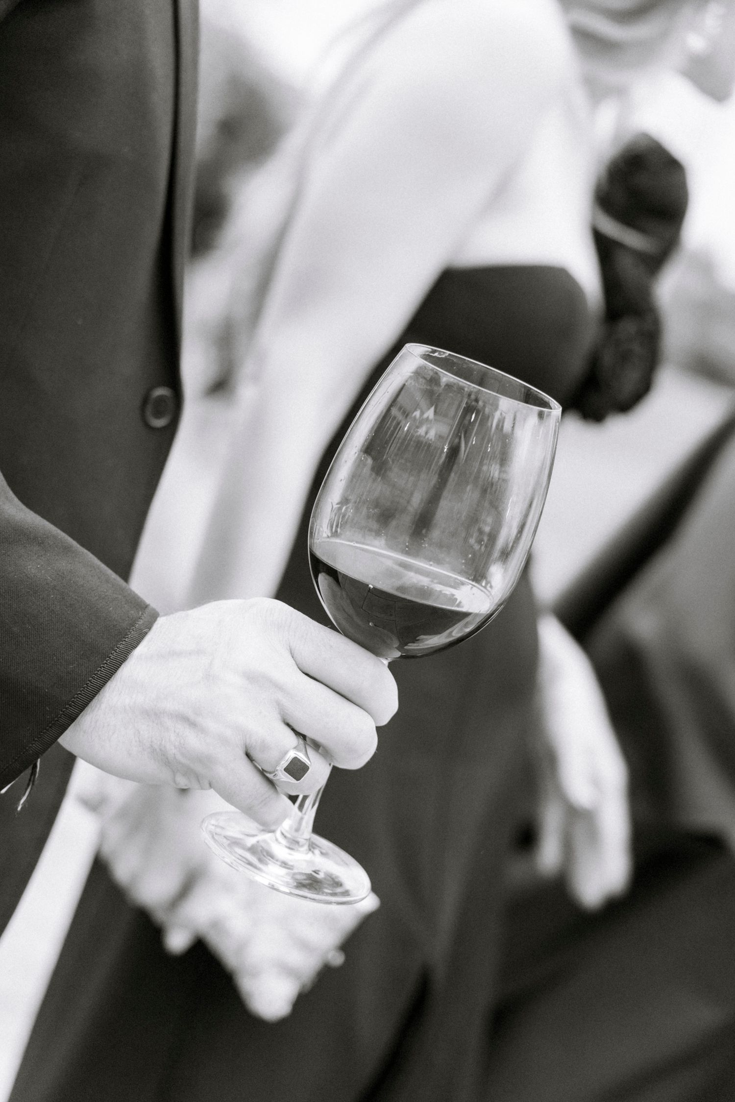 Black and white photo of wine glasses being held during a wedding reception. Rochester NY documentary wedding photography