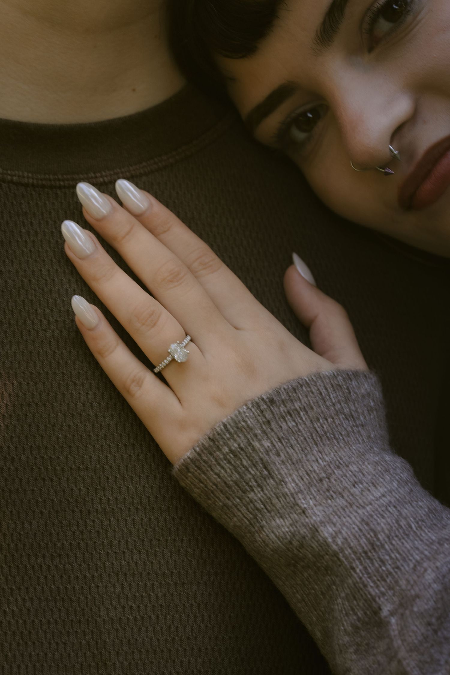 Close-up of hands wearing a gray sweater showing off an engagement ring. Rochester NY documentary engagement photography