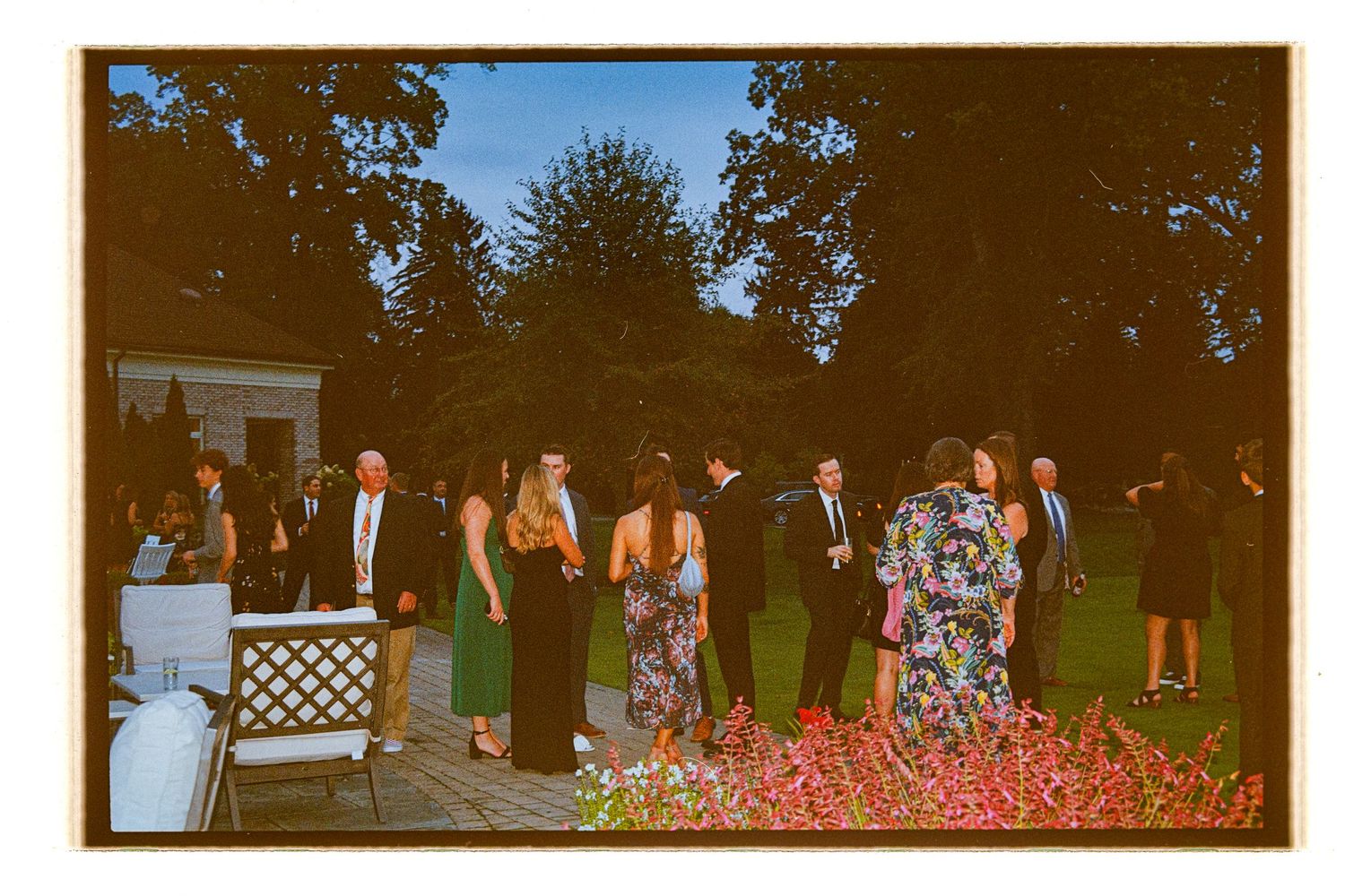 Wedding guests gather on a lush green lawn during an outdoor ceremony. Rochester NY Film wedding photography