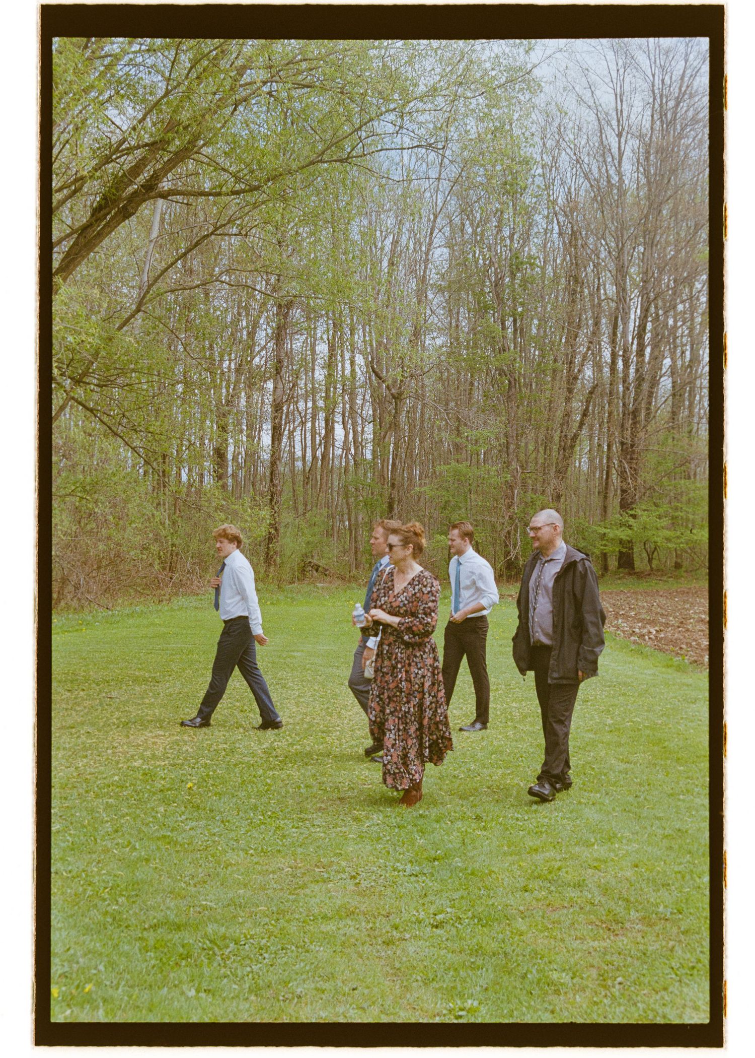 Group walking through a wooded area on grass during an outdoor event.  Camp Brockway Wedding photographer