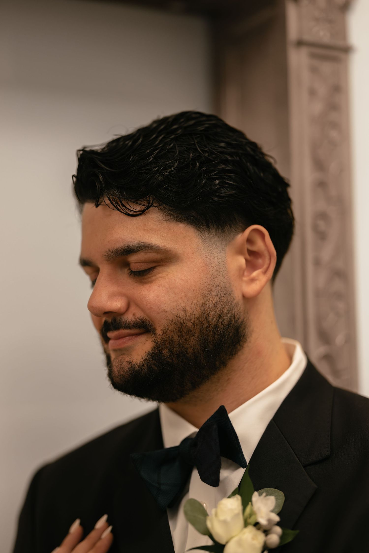 Close-up profile shots of a groom in black suit with white boutonniere showing genuine emotion.