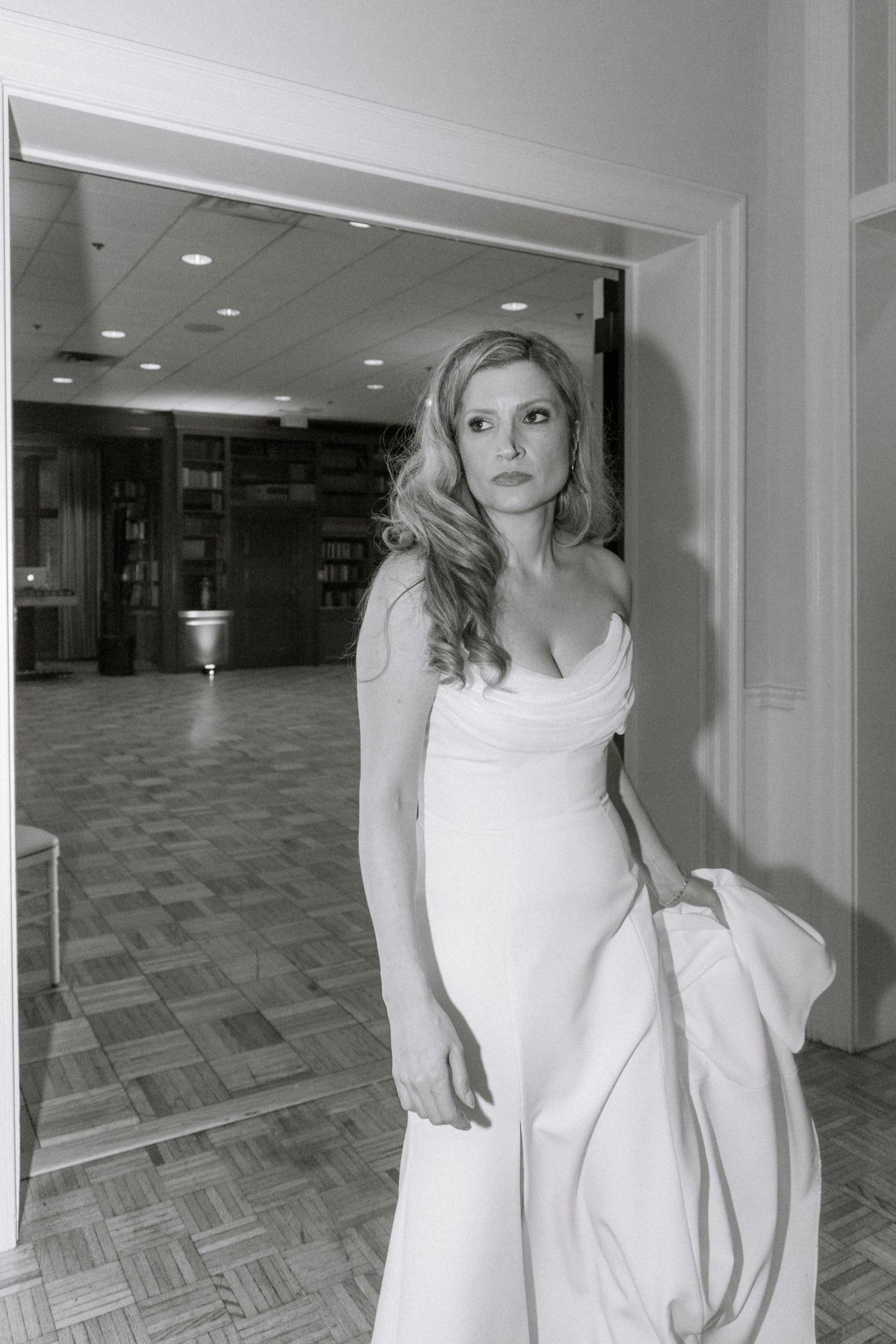 Interior hallway shot showing a flowing white dress against grey flooring. Rochester NY documentary wedding photography