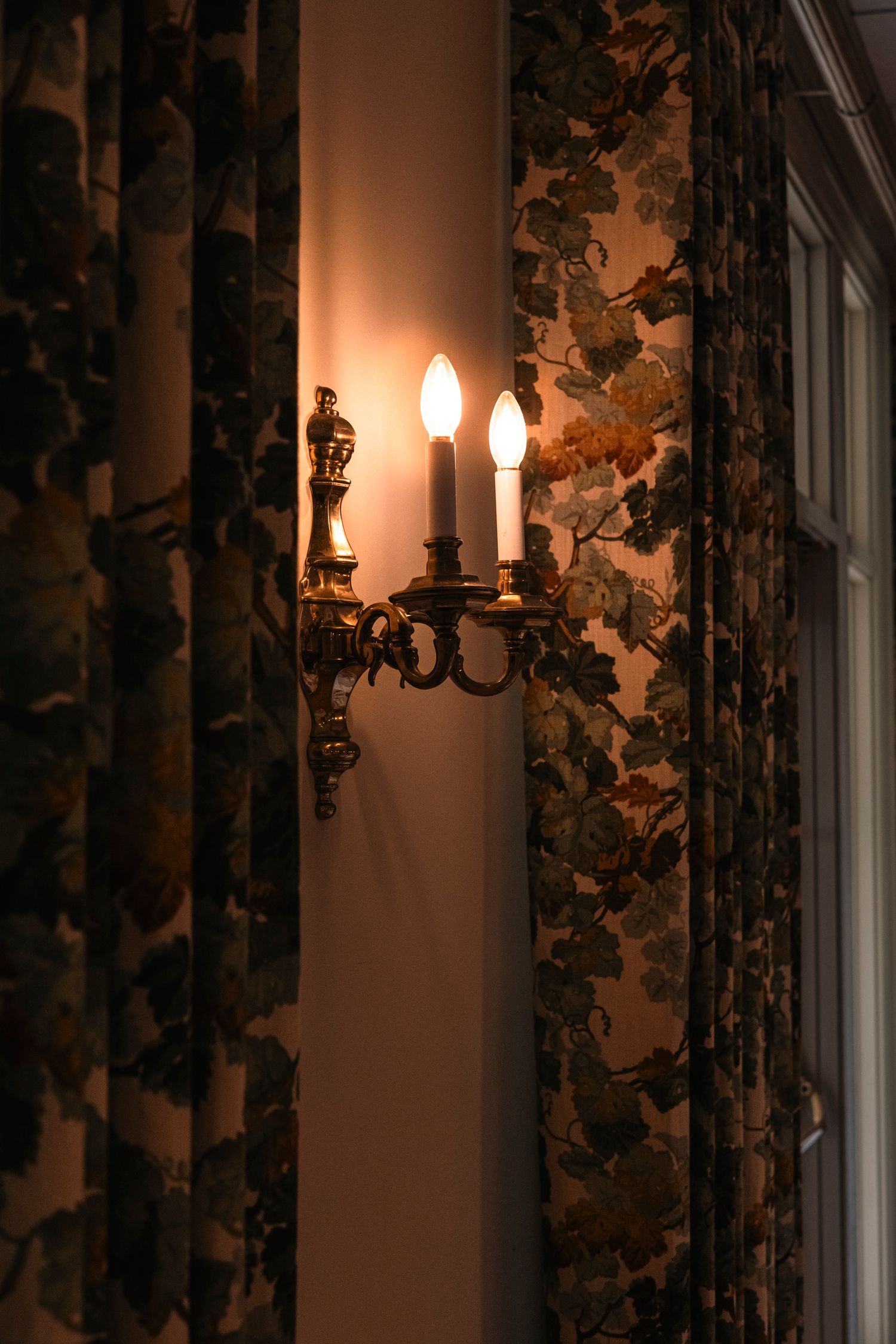 Romantic wall sconces and floral curtains creating ambient lighting.Rochester NY documentary wedding photography